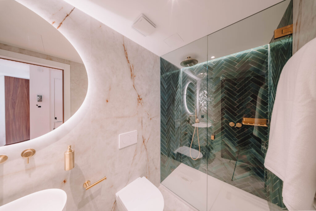 Baño de mármol con ducha de azulejo verde y grifería de latón cepillado