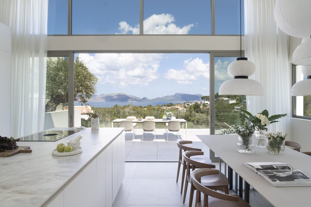 Open-plan kitchen with double-height windows and views over the bay of Pollensa and the mountains